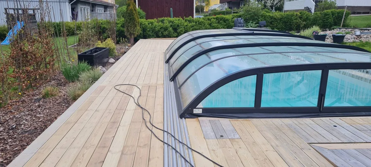 Ny trall av ljust trä runt en pool med glasad överbyggnad